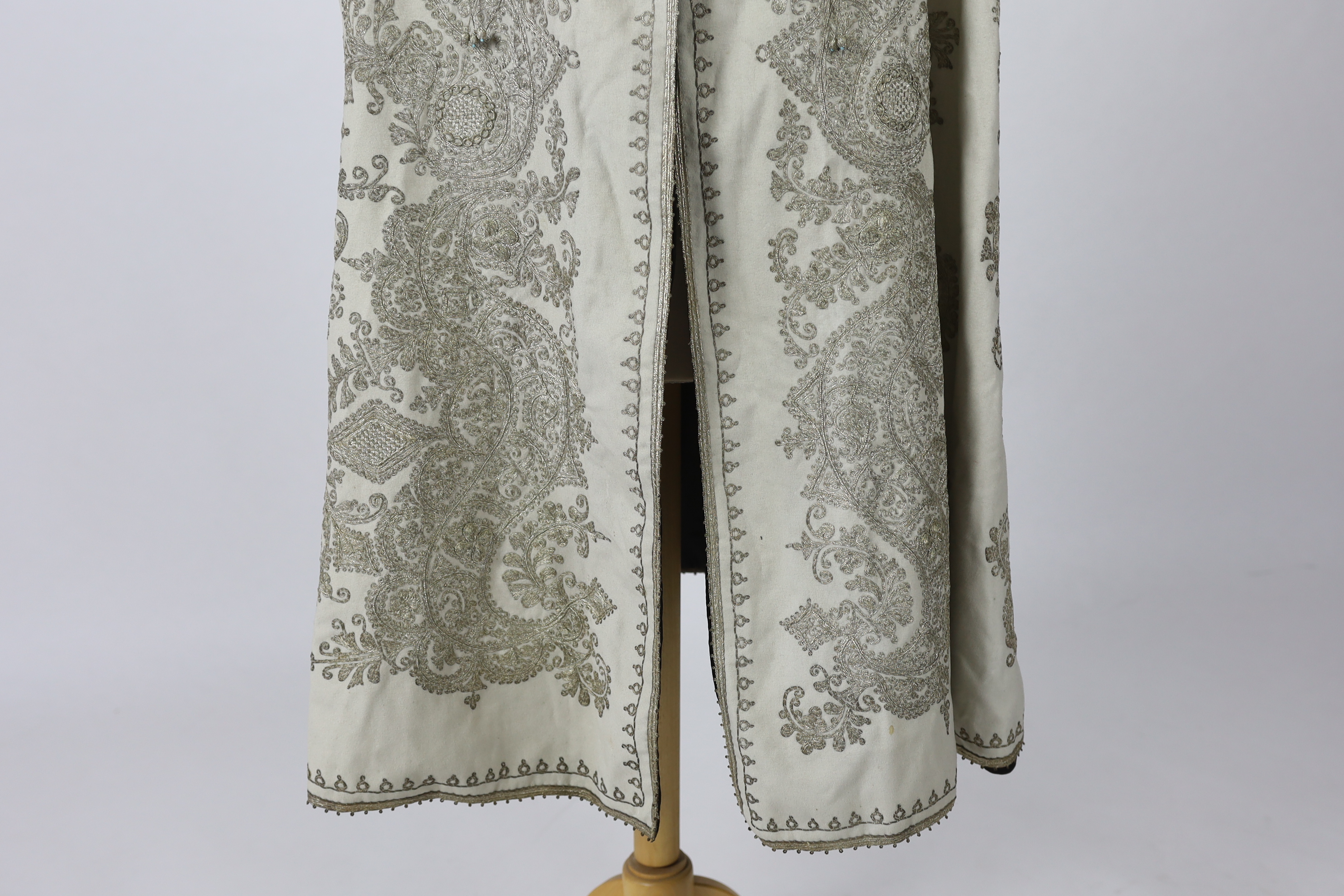 A 19th century Indian fine cream wool embroidered cape, probably made for the European market, embroidered in panels of silver metallic thread in an ornate vertical design with turquoise embellishments and lined in black